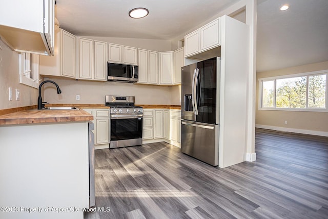 kitchen with sink, butcher block countertops, appliances with stainless steel finishes, hardwood / wood-style flooring, and white cabinets