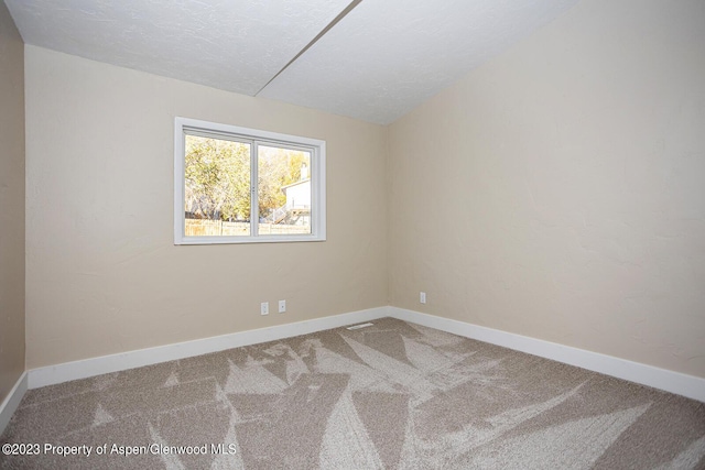 carpeted spare room featuring lofted ceiling and a textured ceiling