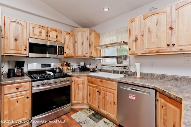 2939 Jon Hall Rd, Grand Junction, CO 81503 - kitchen featuring stainless steel appliances, light brown cabinetry, vaulted ceiling, a sink, and wood finished floors