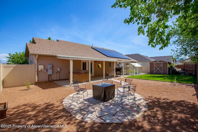 2939 Jon Hall Rd, Grand Junction, CO 81503 - rear view of house with a hot tub, a fenced backyard, a patio, solar panels, and stucco siding