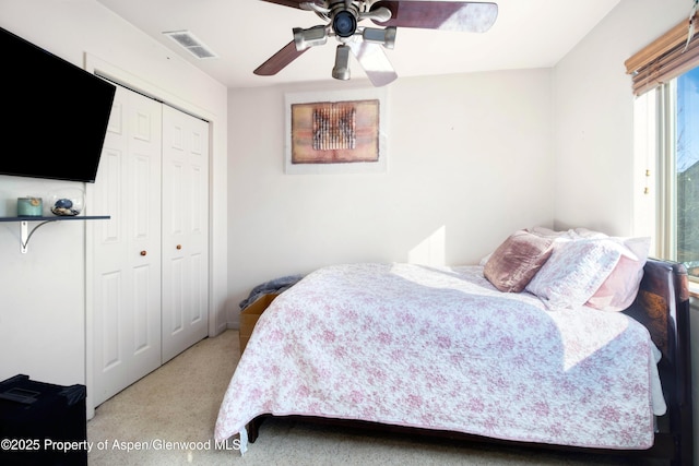 bedroom with a ceiling fan, light colored carpet, a closet, and visible vents