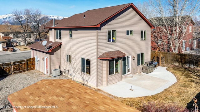 rear view of house with a patio area, a mountain view, a fenced backyard, and central AC unit