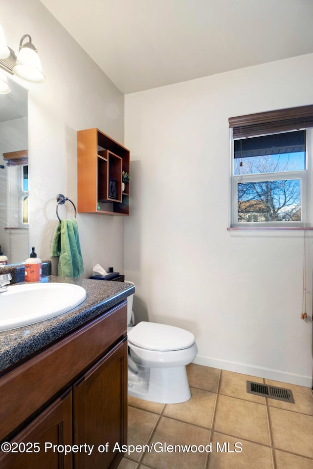 bathroom with toilet, vanity, visible vents, and baseboards