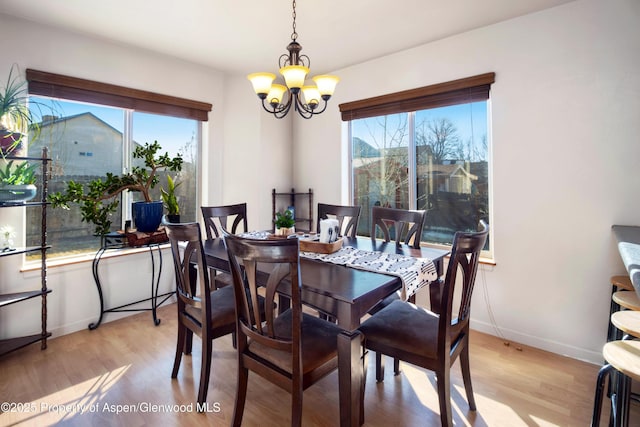 dining area featuring baseboards, light wood-type flooring, and a notable chandelier