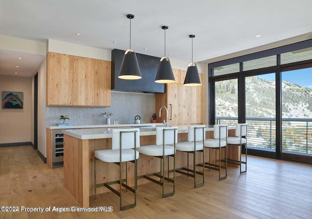 77 Wood Rd Unit 507-10, Snowmass Village, CO 81615 - kitchen with range hood, light countertops, light wood-style flooring, tasteful backsplash, and a large island