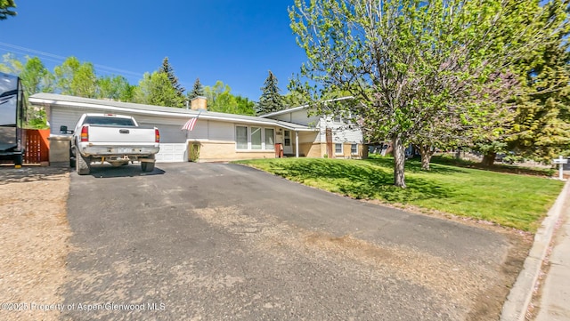 1028 Breeze St, Craig, CO 81625 - view of front of home featuring an attached garage, a chimney, asphalt driveway, a front lawn, and brick siding