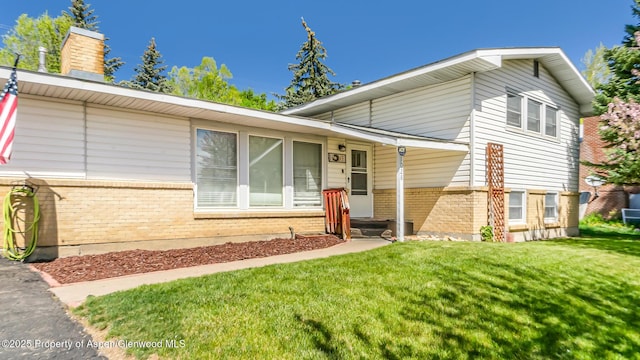 1028 Breeze St, Craig, CO 81625 - tri-level home with brick siding, a front yard, and a chimney