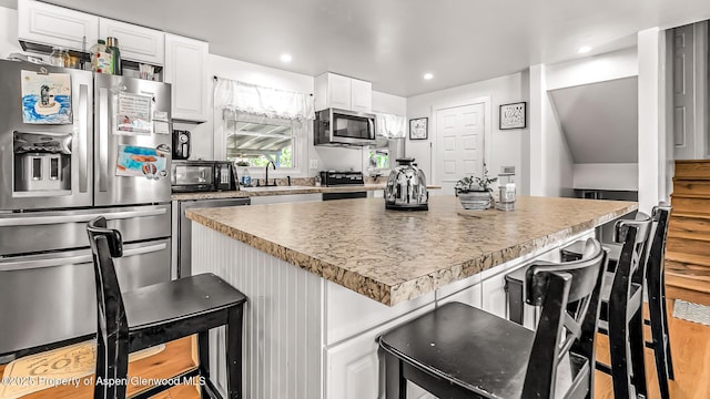 1028 Breeze St, Craig, CO 81625 - kitchen featuring appliances with stainless steel finishes, a sink, white cabinets, a kitchen bar, and recessed lighting