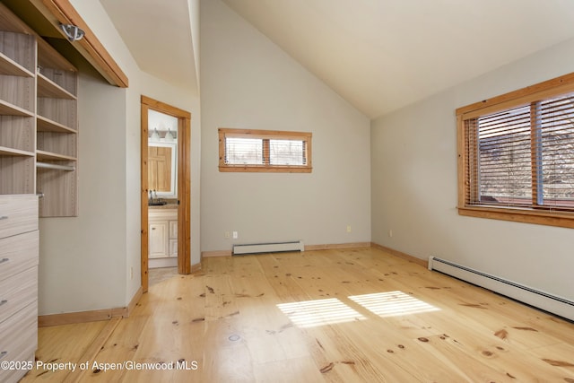 unfurnished bedroom featuring vaulted ceiling, a baseboard heating unit, ensuite bathroom, and light hardwood / wood-style floors