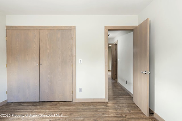 unfurnished bedroom featuring dark hardwood / wood-style flooring and a closet