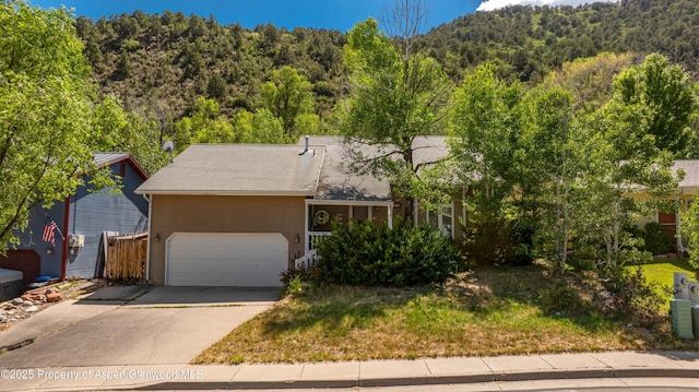 905 Meadow Run, Glenwood Springs, CO 81601 - view of front of home with a wooded view, concrete driveway, and a garage