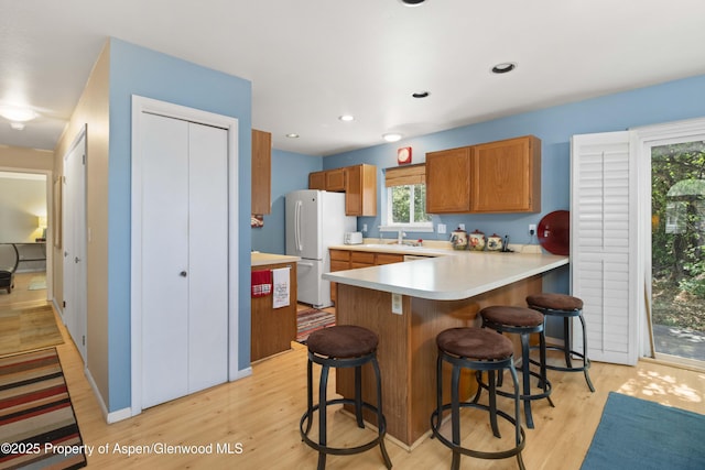 905 Meadow Run, Glenwood Springs, CO 81601 - kitchen featuring light wood finished floors, light countertops, a kitchen bar, freestanding refrigerator, and a peninsula
