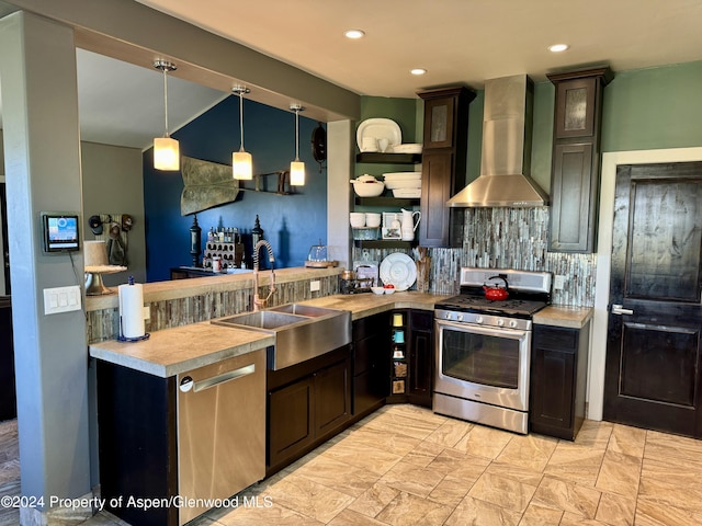 kitchen featuring wall chimney range hood, sink, decorative backsplash, dark brown cabinets, and stainless steel appliances