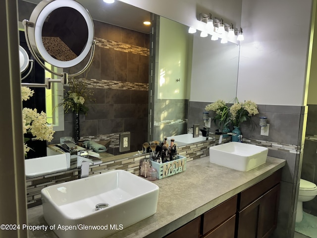 bathroom featuring vanity, toilet, decorative backsplash, and tile walls