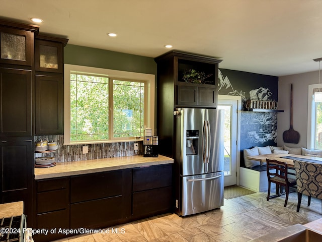 kitchen with stainless steel fridge, dark brown cabinets, and decorative light fixtures