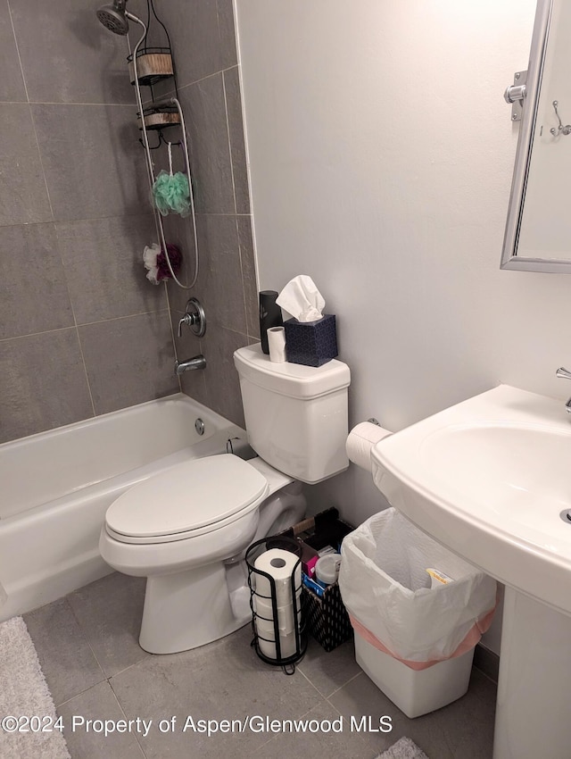 bathroom featuring tile patterned flooring, toilet, and tiled shower / bath