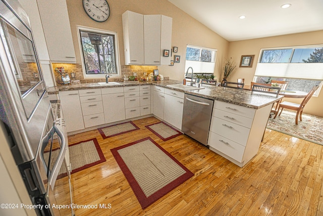 1001 Alta Ct, Craig, CO 81625 - kitchen featuring stainless steel dishwasher, a sink, a peninsula, lofted ceiling, and light wood-style flooring