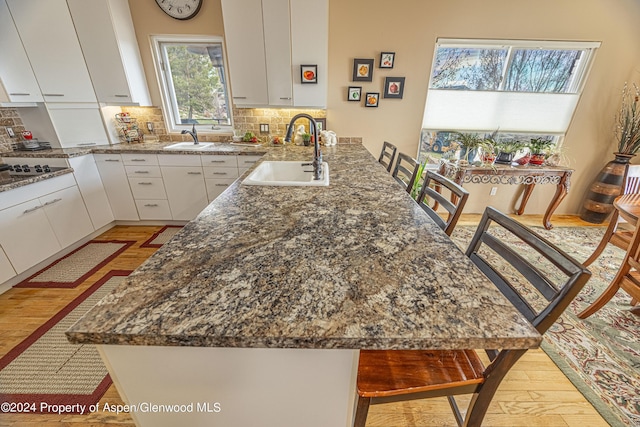 1001 Alta Ct, Craig, CO 81625 - kitchen with a sink, a peninsula, white cabinets, dark stone countertops, and tasteful backsplash
