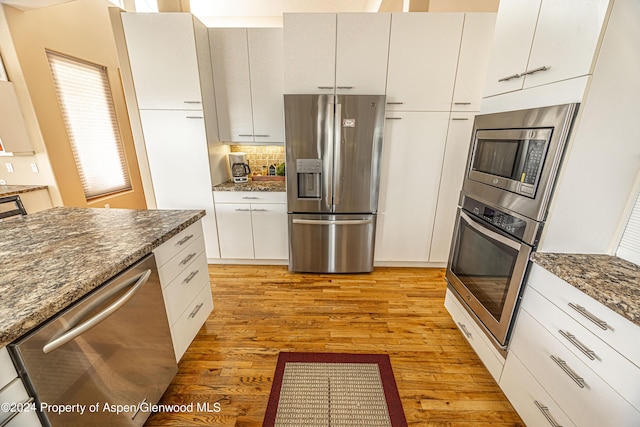 1001 Alta Ct, Craig, CO 81625 - kitchen featuring appliances with stainless steel finishes, light wood-style floors, dark stone counters, backsplash, and white cabinets