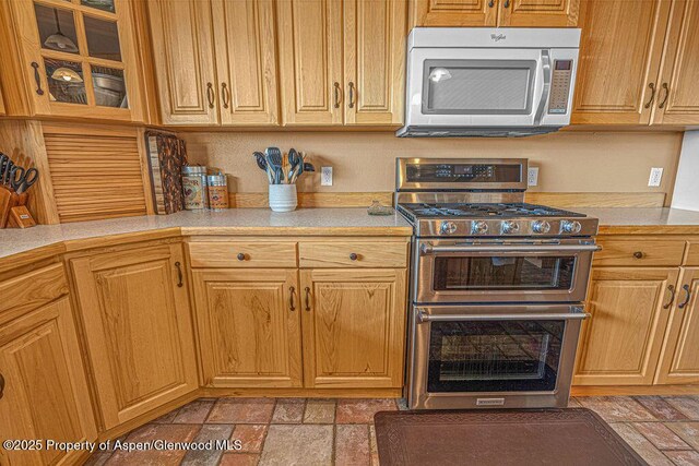 289 Lewis Ln, Craig, CO 81625 - kitchen with appliances with stainless steel finishes, light countertops, stone tile floors, and glass insert cabinets