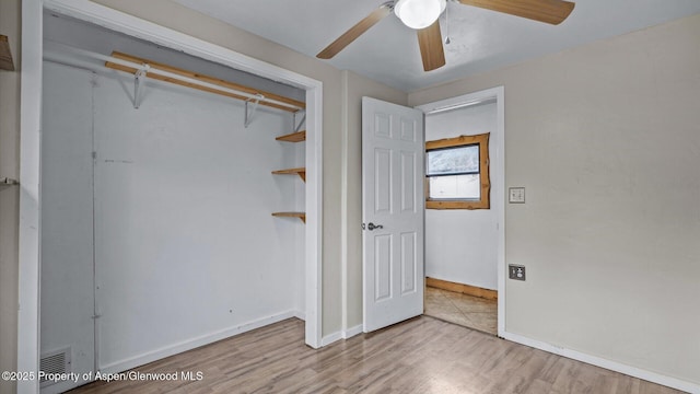 unfurnished bedroom featuring a closet, baseboards, wood finished floors, and a ceiling fan