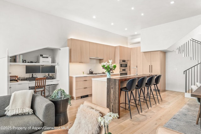 155 Lone Pine Rd Unit 2, Aspen, CO 81611 - kitchen with light brown cabinetry, gas cooktop, a wall mounted air conditioner, a desk, and modern cabinets