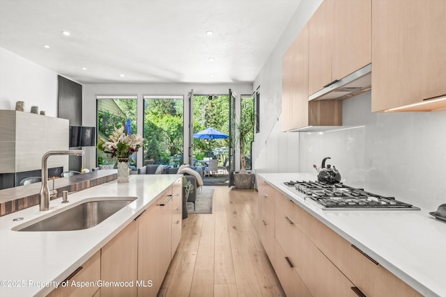 155 Lone Pine Rd Unit 2, Aspen, CO 81611 - kitchen with stainless steel gas stovetop, light brown cabinetry, light countertops, under cabinet range hood, and light wood finished floors
