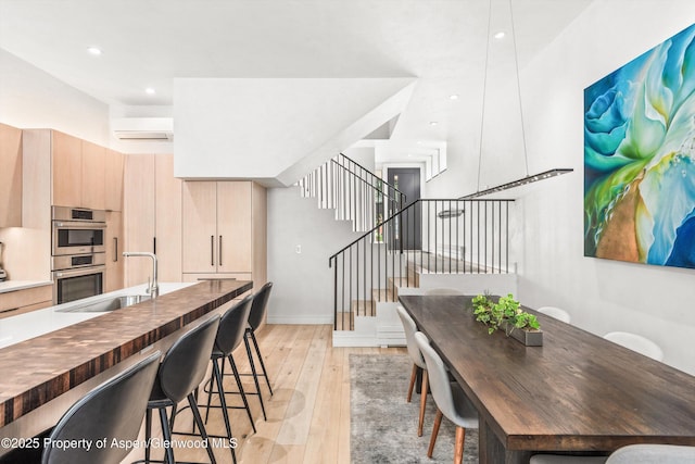 155 Lone Pine Rd Unit 2, Aspen, CO 81611 - dining area with a wall mounted AC, light wood-style flooring, stairway, and recessed lighting