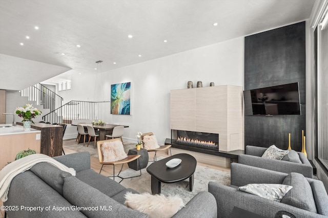 155 Lone Pine Rd Unit 2, Aspen, CO 81611 - living room with stairs, recessed lighting, a warm lit fireplace, and light wood finished floors