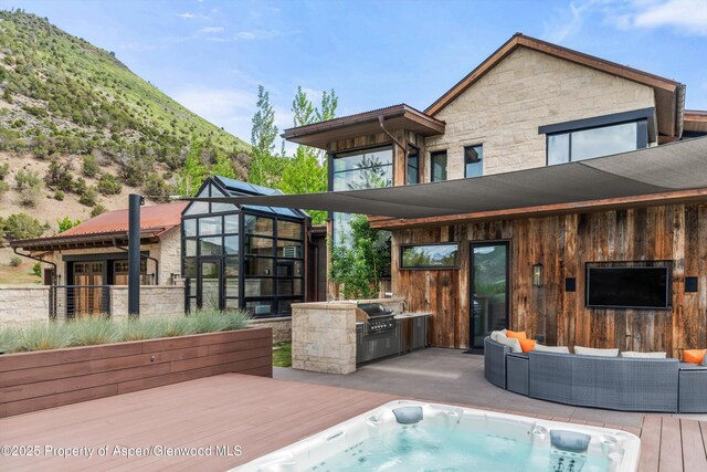 295 Aspen Valley Ranch Rd, Woody Creek, CO 81656 - rear view of house featuring stone siding, an outdoor kitchen, a deck, and an outdoor living space