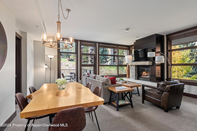 carpeted dining area with a fireplace, a chandelier, and a wealth of natural light