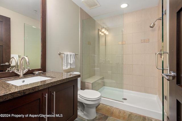 bathroom with vanity, a shower with shower door, and toilet