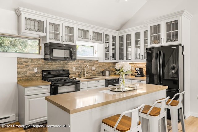 1195 E Cooper Ave Unit A, Aspen, CO 81611 - kitchen featuring black appliances, a baseboard radiator, tasteful backsplash, lofted ceiling, and a kitchen breakfast bar