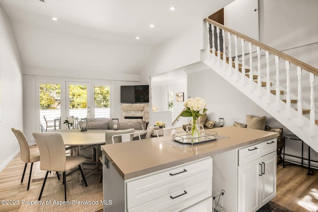 1195 E Cooper Ave Unit A, Aspen, CO 81611 - kitchen featuring lofted ceiling, light wood-type flooring, a fireplace, white cabinets, and recessed lighting