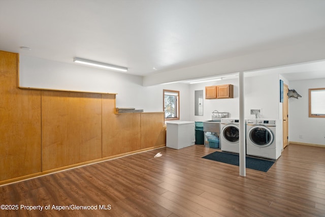 washroom featuring a wainscoted wall, cabinet space, washing machine and dryer, wood finished floors, and electric panel