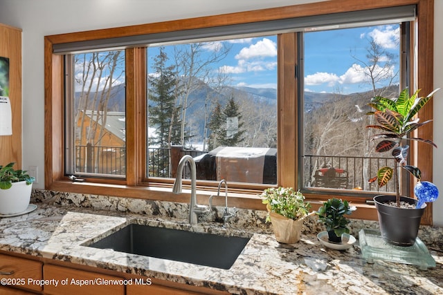 kitchen with a sink, a mountain view, and light stone countertops