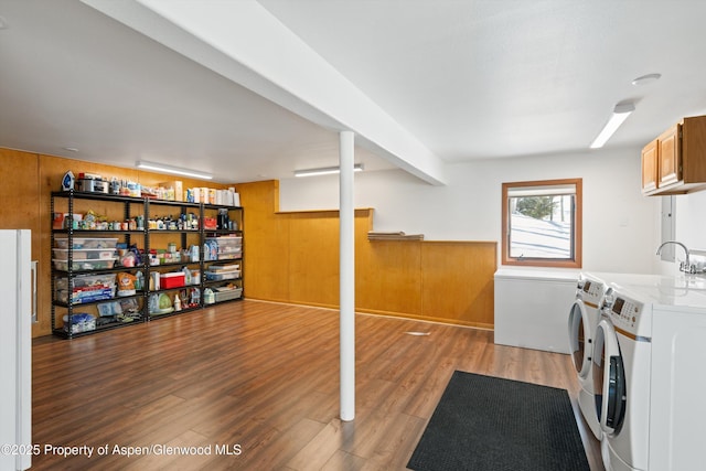 washroom featuring wooden walls, a wainscoted wall, washer and dryer, cabinet space, and light wood finished floors