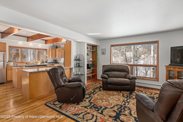 living area featuring light wood-type flooring, baseboard heating, and beam ceiling