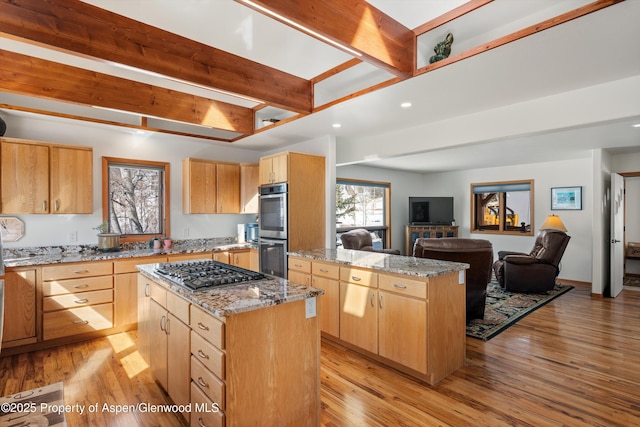 kitchen with a kitchen island, appliances with stainless steel finishes, open floor plan, and light brown cabinetry