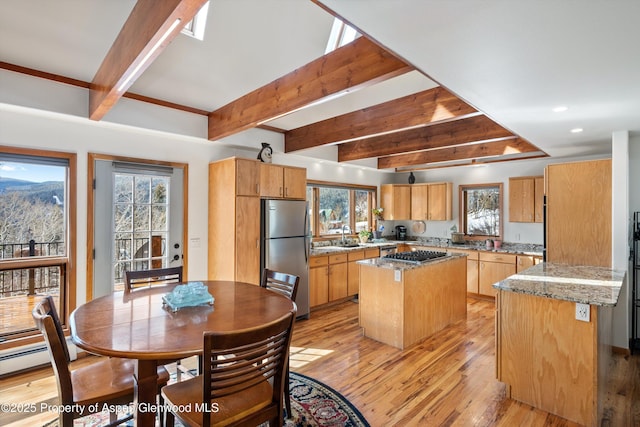 kitchen with recessed lighting, appliances with stainless steel finishes, beam ceiling, a center island, and light wood finished floors