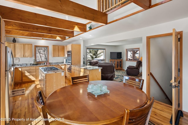 dining room featuring light wood-style flooring and beamed ceiling