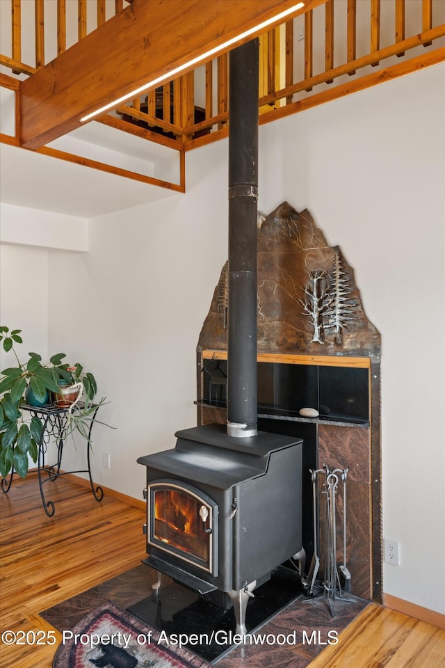 room details with a wood stove, baseboards, and wood finished floors