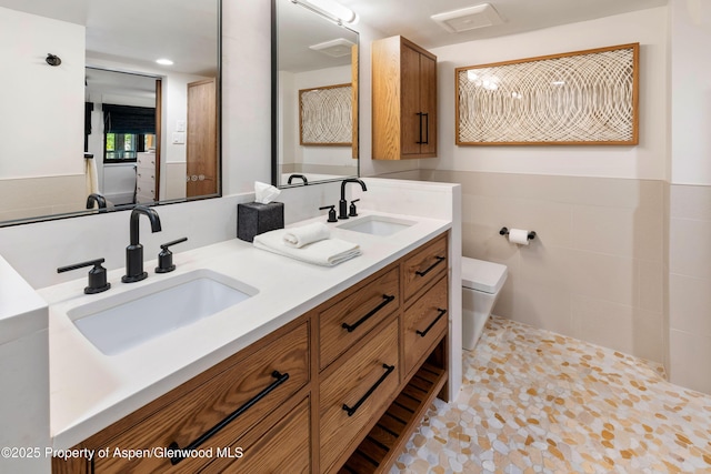 800 S Mill St Unit 105, Aspen, CO 81611 - full bath featuring toilet, double vanity, a wainscoted wall, and tile walls