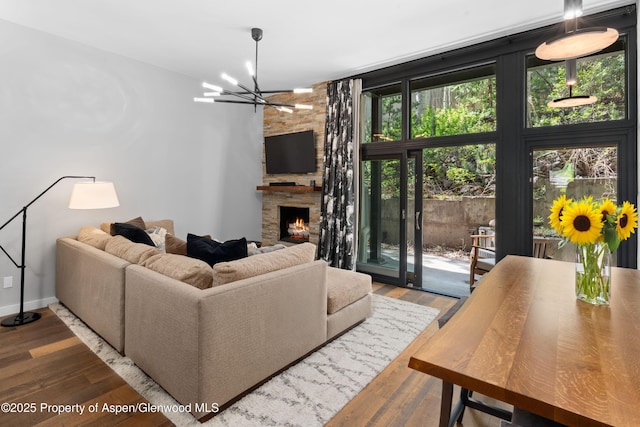 800 S Mill St Unit 105, Aspen, CO 81611 - living area with a fireplace, wood finished floors, a chandelier, and baseboards