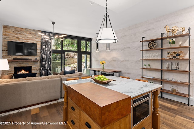 800 S Mill St Unit 105, Aspen, CO 81611 - kitchen with dark wood finished floors, a fireplace, open floor plan, and pendant lighting