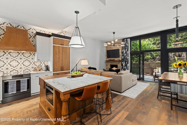 800 S Mill St Unit 105, Aspen, CO 81611 - kitchen with backsplash, wood finished floors, a center island, wall oven, and vaulted ceiling