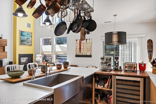 kitchen featuring decorative light fixtures, butcher block counters, sink, and beverage cooler