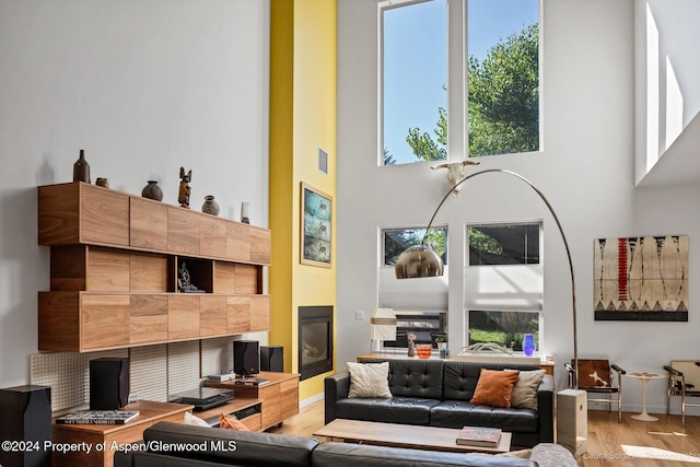 living room featuring hardwood / wood-style floors, a high ceiling, and a tiled fireplace