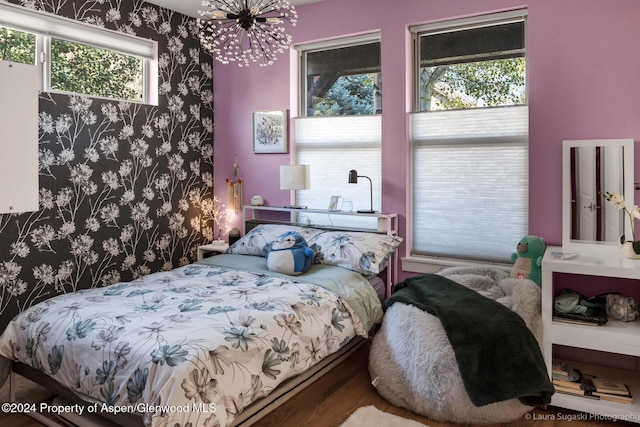 bedroom with hardwood / wood-style floors and a chandelier