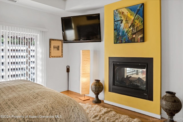 bedroom featuring hardwood / wood-style flooring and a multi sided fireplace